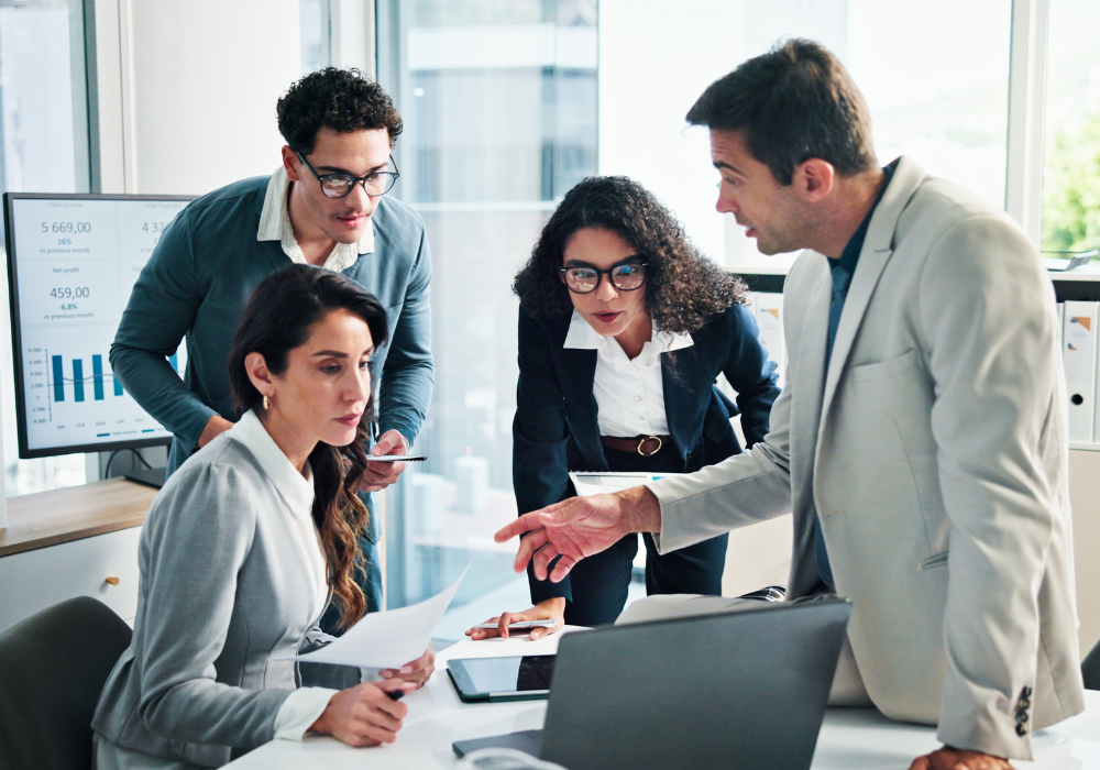 A business team gathered around a desk reviewing financial reports and planning an enterprise automation budget.